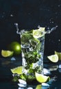 Mojito with splash and drops. Cocktail or mocktail with lime, mint, and ice in glass on blue background. Summer cold alcoholic non Royalty Free Stock Photo