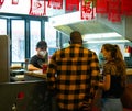 People wearing face masks placing an order at a food stall.