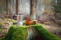 Moka pot coffee maker and wooden cup kuksa on a beautiful moss covered stump. The background of the forest is blurred Royalty Free Stock Photo