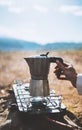 Moka pot coffee outdoor, campsite morning picnic lifestyle, person cooking hot drink in nature camping, prepare breakfast, tourism