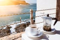 Moka pot espresso maker and cup of coffee on table with coastline and ocean in background Royalty Free Stock Photo