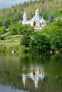 Moldavian monastery mirrored in water, summer landscape, white stone church