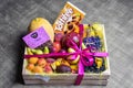 Variety of ripe fruits and berries are beautifully stacked in wooden box tied with pink ribbon. Dark background. Food delivery,