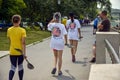 Moldova, Rybnitsa - July 2021: Young female athletes carry paddles after kayak race. Back view. Crowded river embankment