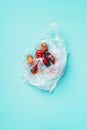 Moldy and wrinkled rotten peppers in plastic bag on blue background. Concept of unhealthy, decompose, spoiled vegetables. Garbage