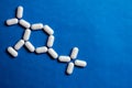 Molecule model made of pills. Medical concept of drug formula on blue paper background.