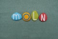 Moln, swedish word meaning cloud composed with multi colored stone letters over green sand