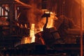 Molten iron pouring from ladle container into mold, workers control process, steel foundry factory, heavy metallurgy