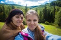 Mom and adult daughter sitting on the top of mountains and taking selfie Royalty Free Stock Photo