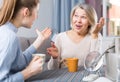 Mom and adult daughter talk and drink tea in the kitchen