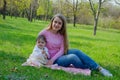 Mom with baby in bright clothes on a pink plaid on the green right. Family resting in the park on a warm day