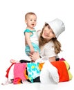 Mom and baby girl with suitcase and clothes ready for traveling Royalty Free Stock Photo