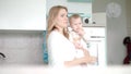 Mom with baby going in white kitchen. Beauty woman with little child on hand Royalty Free Stock Photo