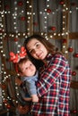 Mom and baby hug at the Christmas tree. Happy baby and his mom are looking at the frame. Mom with son hugging for Christmas. and Royalty Free Stock Photo