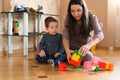 Mom and baby are playing on the floor. Beautiful baby plays with toys with happy mother indoors Royalty Free Stock Photo