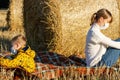 Mom and baby sit on the ground in nature on the background of haystacks Royalty Free Stock Photo