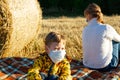 Mom and baby sit on the ground in nature on the background of haystacks Royalty Free Stock Photo