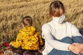 Mom and baby sit on the ground in nature of haystacks in medical masks Royalty Free Stock Photo