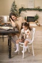 Mom and baby are sitting at table with jar full of ginger cookies. The girl takes out gingerbread from the can. Royalty Free Stock Photo