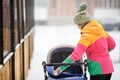 Mom and baby in stroller on walk, snowy winter weather. Snowfall, blizzard, outdoor. Royalty Free Stock Photo