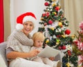 Mom and baby using tablet PC near Christmas tree