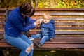 Mom on a bench in the park wipes the baby face with a napkin, which got dirty while playing for a walk. close-up, soft Royalty Free Stock Photo