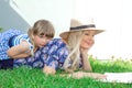 Mom blonde in a hat and her daughter are lying on the grass and reading a book, happy family. Royalty Free Stock Photo