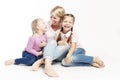 Mom blonde with small daughters hug and laugh. A happy family. White background Royalty Free Stock Photo