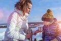 Mom with a boy son 3 years old, in the winter in a pair in the fresh air. Rest at the weekend resort, on the bench, a