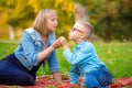 Mom and boy teen sit on green glade and blow off dandelion Royalty Free Stock Photo