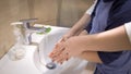 Mom and boy washing hands together. Mother helps her son directing arms under running water. Parenthood concept. Side Royalty Free Stock Photo