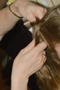 Mom braids her daughter`s hair. women`s hands weave a braid on the girl`s head.