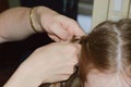 Mom braids her daughter`s hair. women`s hands weave a braid on the girl`s head.