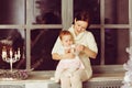 Mom brunette sitting on window and hugs the little cute chubby g Royalty Free Stock Photo