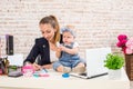 Mom and businesswoman working with laptop computer at home and playing with her baby girl. Royalty Free Stock Photo