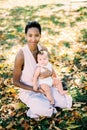 Mom with a child on her lap sits on yellow foliage