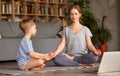 Mom with child little son doing yoga online, sitting in lotus pose on floor and meditating with closed eyes Royalty Free Stock Photo