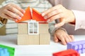 Mom and child build a house of wooden cubes and blocks constructor. Close up of hands holding roof elements. Playing parents and Royalty Free Stock Photo