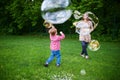 Mom and children playing soap bubbles on the green lawn in the park Royalty Free Stock Photo