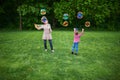 Mom and children playing soap bubbles on the green lawn in the park Royalty Free Stock Photo