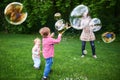 Mom and children playing soap bubbles on the green lawn in the park Royalty Free Stock Photo