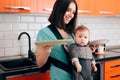 Mother Holding Dishes Holding  Baby in Carrier Royalty Free Stock Photo