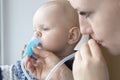 Mom cleans baby`s nose using a nasal aspirator Royalty Free Stock Photo