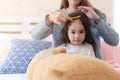 Mom comb her lovely little asian daughter on bed at bedroom. Cute Asia child is innocent girl. Nursery child feel happy and