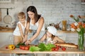 Mom cooks lunch with the kids. A woman teaches her daughter to cook from her son. Vegetarianism and healthy natural food. Royalty Free Stock Photo