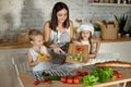 Mom cooks lunch with the kids. A woman teaches her daughter to cook from her son. Vegetarianism and healthy natural food. Royalty Free Stock Photo