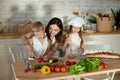 Mom cooks lunch with the kids. A woman teaches her daughter to cook from her son. Vegetarianism and healthy natural food. Royalty Free Stock Photo