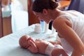 Mom with cute smile takes care of her newborn boy on baby changing table Royalty Free Stock Photo