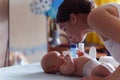 Mom with cute smile takes care of her newborn boy on baby changing table Royalty Free Stock Photo