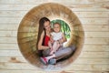 Mom and cute toddler sitting in natural playground. Eco-friendly playground